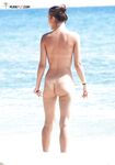 A lady perfecting her golden tan at a beach where tops are unnecessary. 2