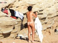 A lady perfecting her golden tan at a beach where tops are unnecessary. 2