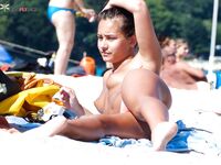 Topless opalování na písku v oranžových spodních dílech bikiny