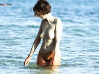 A lady enjoying the rhythmic sound of the waves in a relaxed, clothing-free manner.