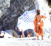 Nahý okamžik na skalnatém pobřeží s oranžovým ručníkem