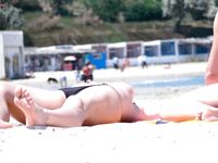 A lady enjoying a refreshing walk while sunbathing topless on the shoreline.