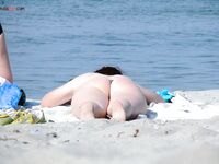 Modré spodní díly bikiny a bílý klobouk na slunném písku