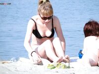 Modré spodní díly bikiny a bílý klobouk na slunném písku