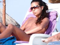 Lounging Topless on a Sandy Beach Chair With a Purple Towel