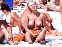 Feeling the heat of the sand while lounging topless at a private sandy cove.