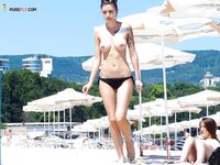 Embracing the warmth of the sand and the coolness of the sea in a topless fashion.