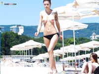 Embracing the warmth of the sand and the coolness of the sea in a topless fashion.