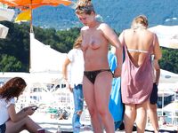 Embracing the warmth of the sand and the coolness of the sea in a topless fashion.