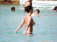 Phone in Hand in the Shallow Surf Along a Rocky Topless Beach
