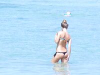 Phone in Hand in the Shallow Surf Along a Rocky Topless Beach