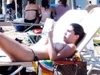 Phone in Hand in the Shallow Surf Along a Rocky Topless Beach