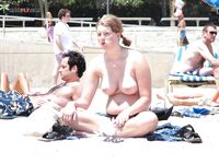 Distesa sull'asciugamano marrone vicino alla rete da volley in spiaggia topless
