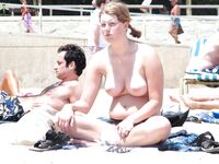 Distesa sull'asciugamano marrone vicino alla rete da volley in spiaggia topless