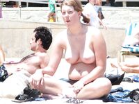 Distesa sull'asciugamano marrone vicino alla rete da volley in spiaggia topless