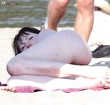 A model relaxing in the warm sand in a natural, completely nude state.