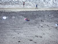 DSLR Raised to Frame the Pebbled Shoreline Beside Shallow Waves