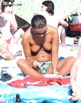 Three Topless Women Pose as One Lifts a Compact Camera