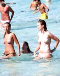 Three Topless Women Pose as One Lifts a Compact Camera