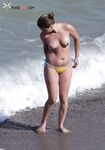 A lady enjoying a tropical-style beach in a traditional topless manner.