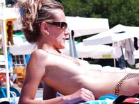Spreading a Turquoise Towel on Wet Sand at the Nude Beach Shore