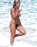 Capelli bagnati raccolti emergendo dalla bassa marea sulla spiaggia topless