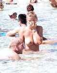 Occhiali da sole in testa nell'acqua bassa della spiaggia affollata