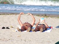 Two Nudists Unwind on Towels as Waves Roll In