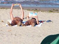 Two Nudists Unwind on Towels as Waves Roll In