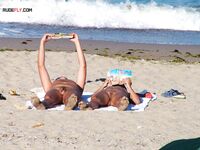 Two Nudists Unwind on Towels as Waves Roll In
