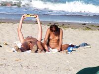 Two Nudists Unwind on Towels as Waves Roll In