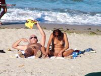 Two Nudists Unwind on Towels as Waves Roll In