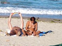Two Nudists Unwind on Towels as Waves Roll In