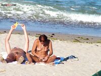 Two Nudists Unwind on Towels as Waves Roll In