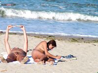 Two Nudists Unwind on Towels as Waves Roll In