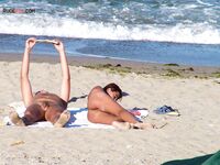 Two Nudists Unwind on Towels as Waves Roll In