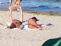Two Nudists Unwind on Towels as Waves Roll In
