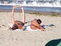 Two Nudists Unwind on Towels as Waves Roll In