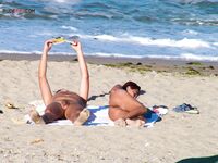 Two Nudists Unwind on Towels as Waves Roll In