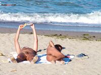 Two Nudists Unwind on Towels as Waves Roll In