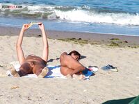 Two Nudists Unwind on Towels as Waves Roll In