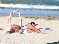Two Nudists Unwind on Towels as Waves Roll In