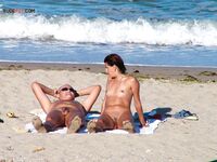 Two Nudists Unwind on Towels as Waves Roll In