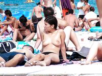 El pelo mojado brilla sobre el agua turquesa al salir del mar en playa nudista