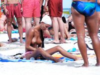 El pelo mojado brilla sobre el agua turquesa al salir del mar en playa nudista