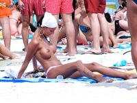 El pelo mojado brilla sobre el agua turquesa al salir del mar en playa nudista