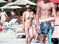 Upright Beside a Straw Sunshade on a Midday Topless Beach