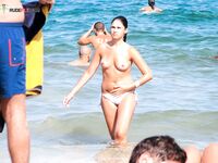 Oranžové spodní díly a šplouchání v mělčinách na topless pláži