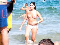 Oranžové spodní díly a šplouchání v mělčinách na topless pláži