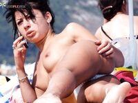 One Woman Topless at the Shoreline Holding a Phone